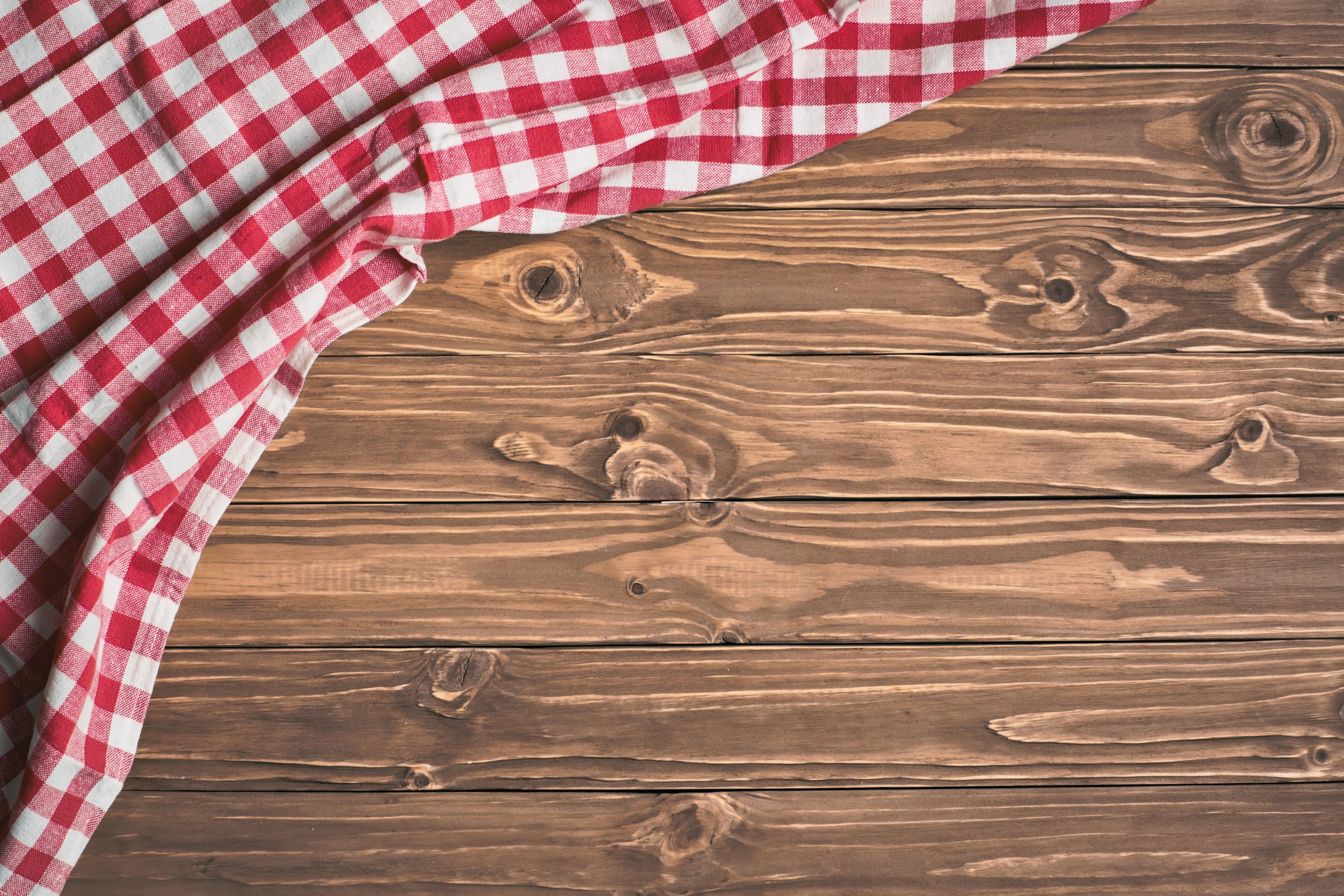 Red checkered tablecloth on wooden table. Background with copy space. Horizontal. Top view.